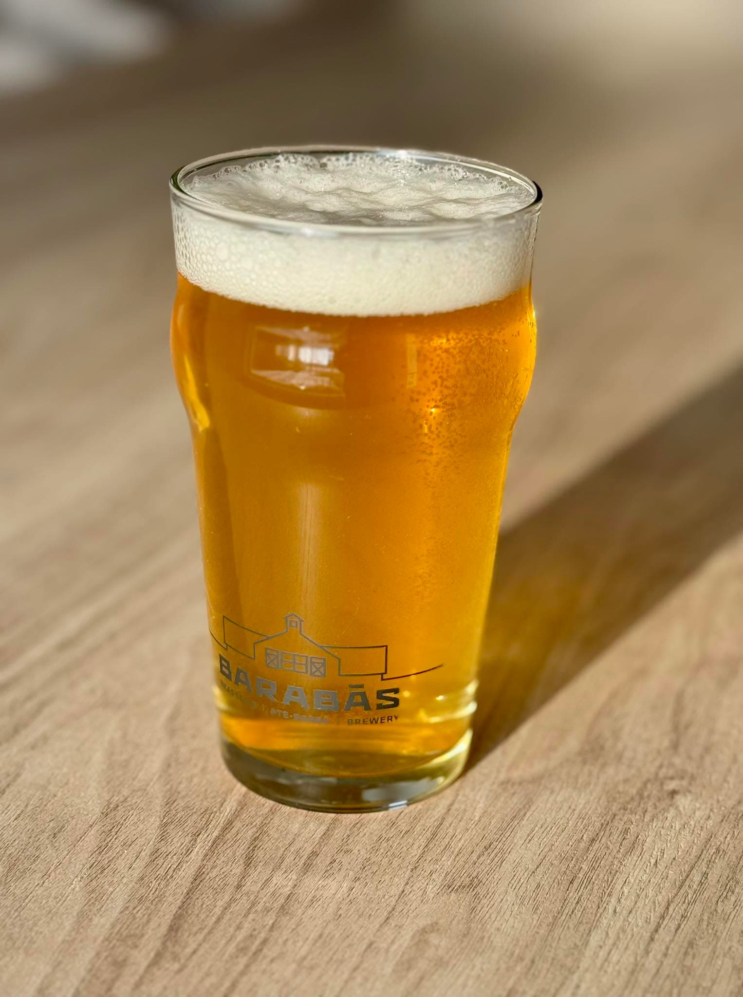 Une pinte de bière blonde Barabās sur une table de bois